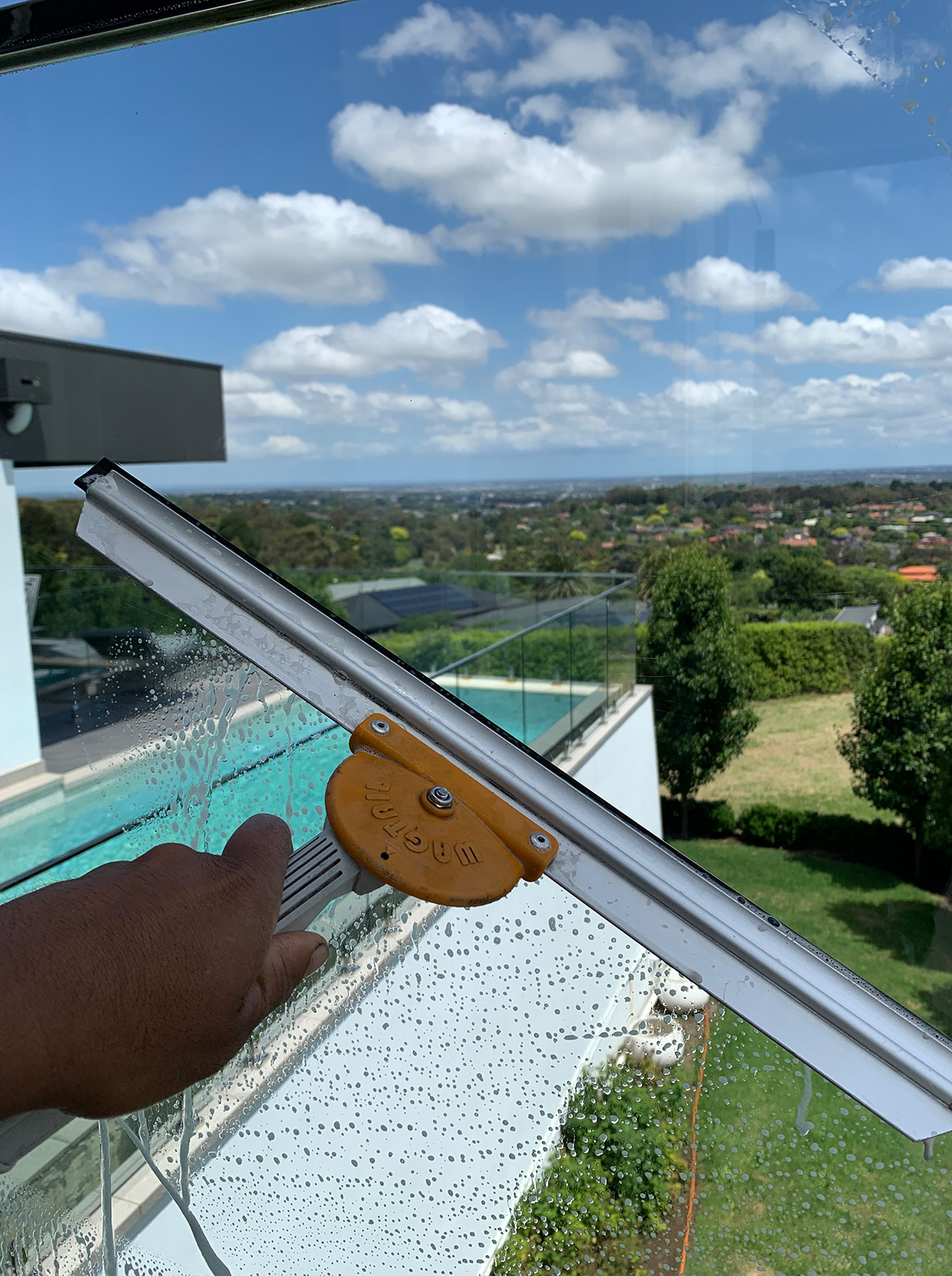 A squeegee cleaning glass overlooking a garden
